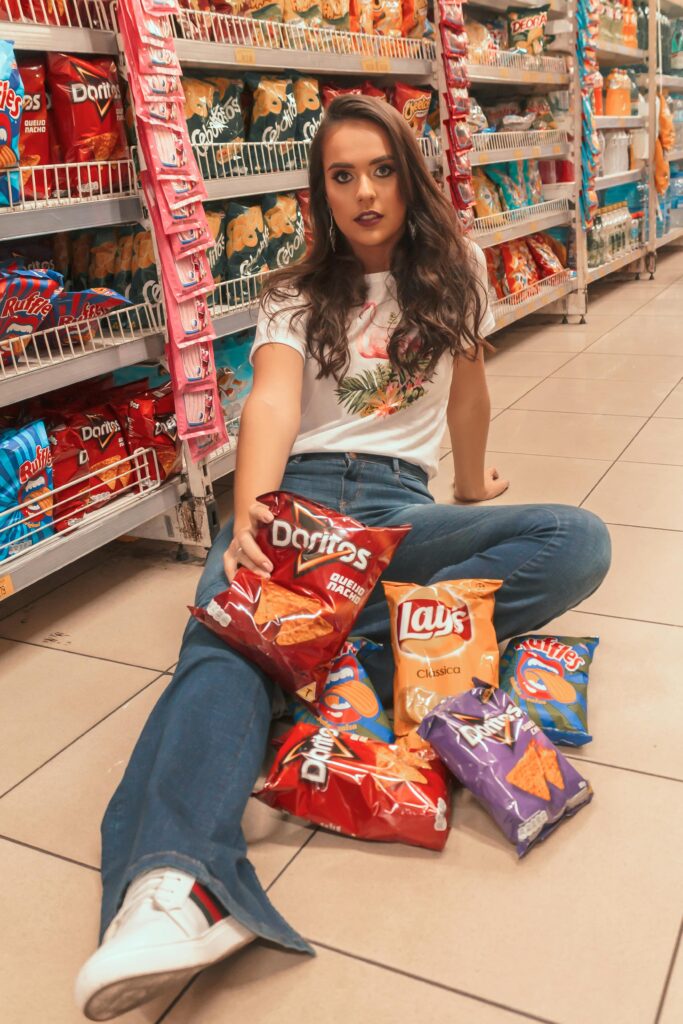 pexels-photo-2121323-2121323 Young woman with trendy style sits on supermarket floor surrounded by snack bags.
